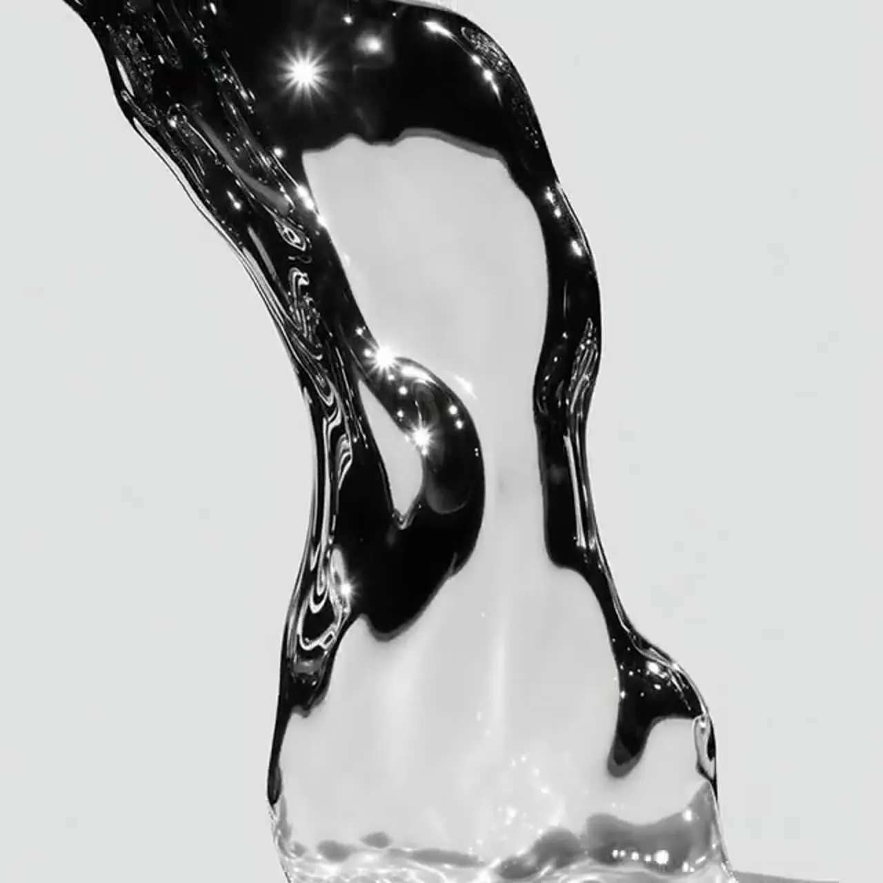 A macro pour of clear water catching points of light against pale grey: present and in motion, yet almost impossible to see.